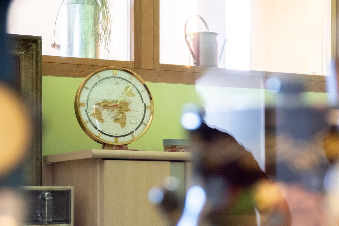 Antike Tisch-Uhr mit mit Weltkarte auf dem Ziffernblatt steht auf einer Kommode in einem Pflegeheim.