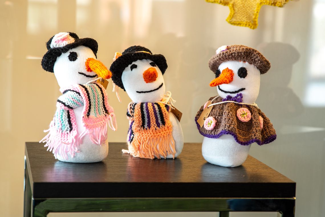 Drei aus alten Socken gebastelte Schneemänner stehen zusammen und scheinen eine Konversation zu führen.